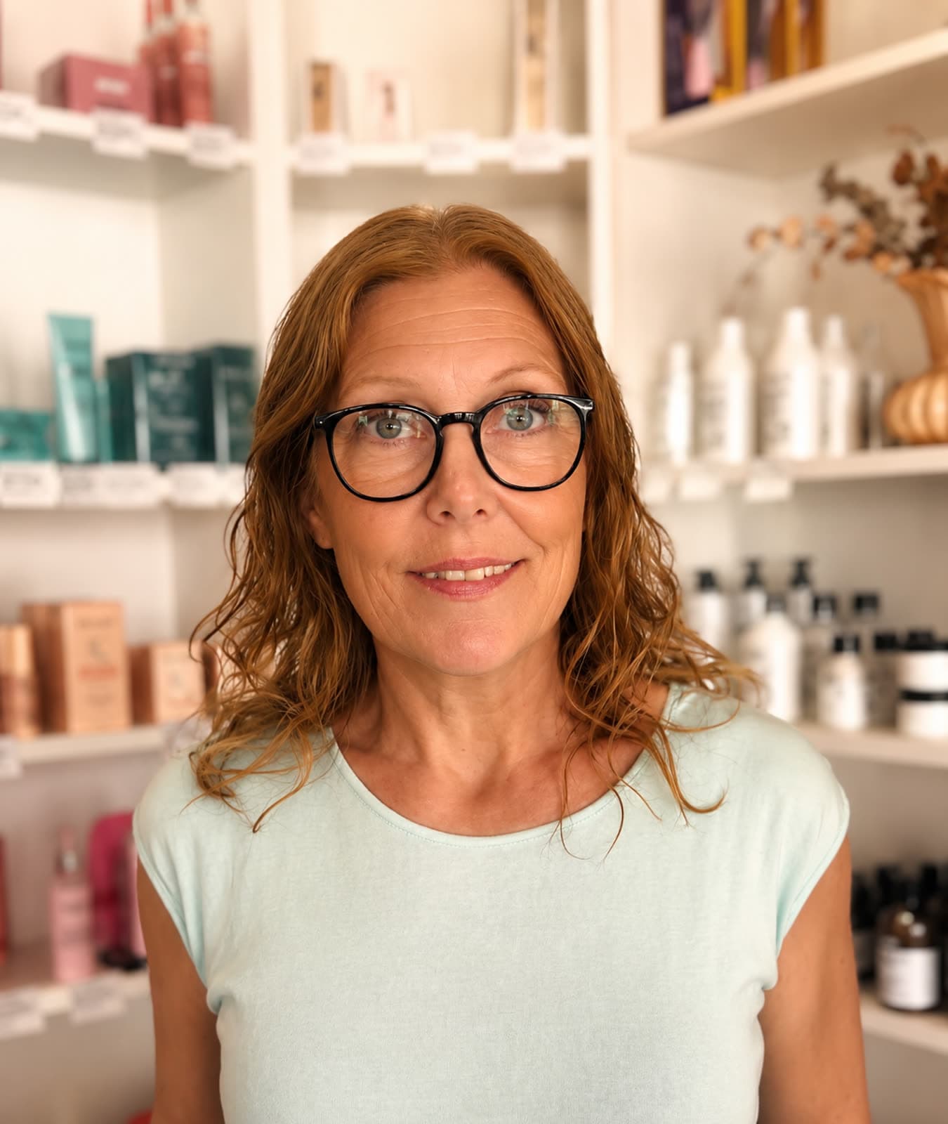 Helena i salongen, framför hyllorna med hudvårdsprodukter