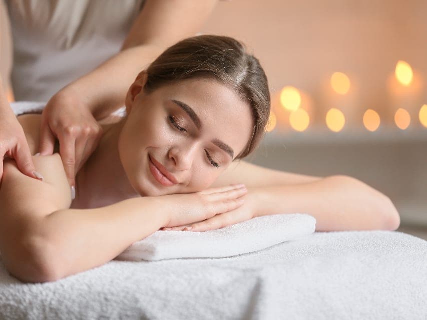 Ryggmassage i varmt ljus, med händerna mot skuldran